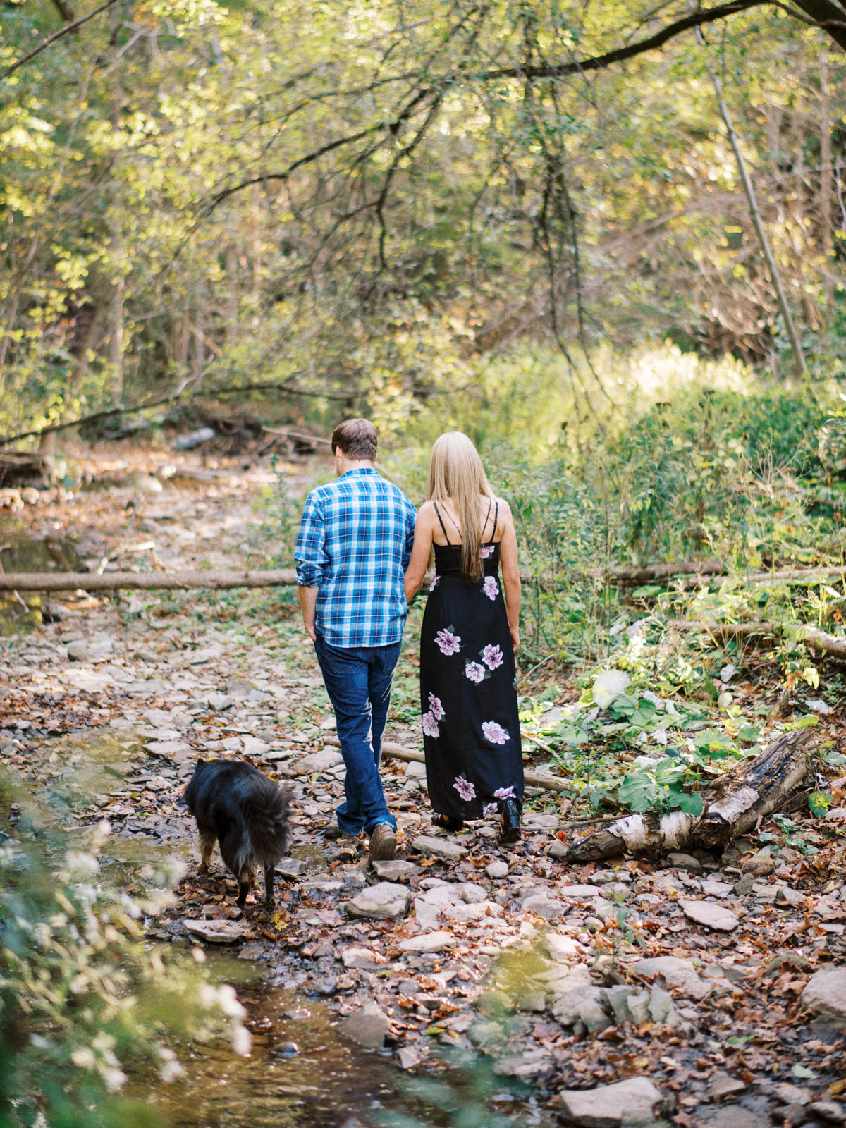 a couple walking along the creek with their dog during an engagement session
