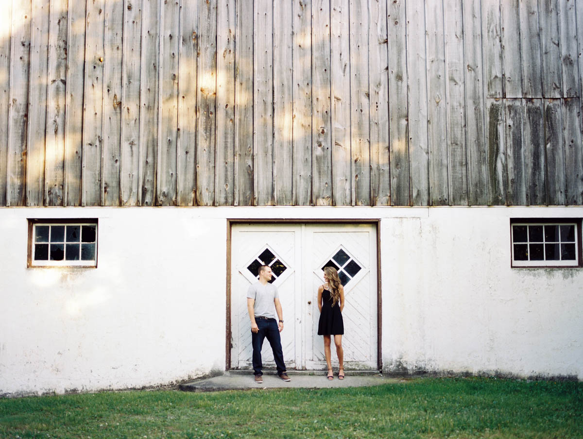 couple standing in the barn doors during an engagement photography session